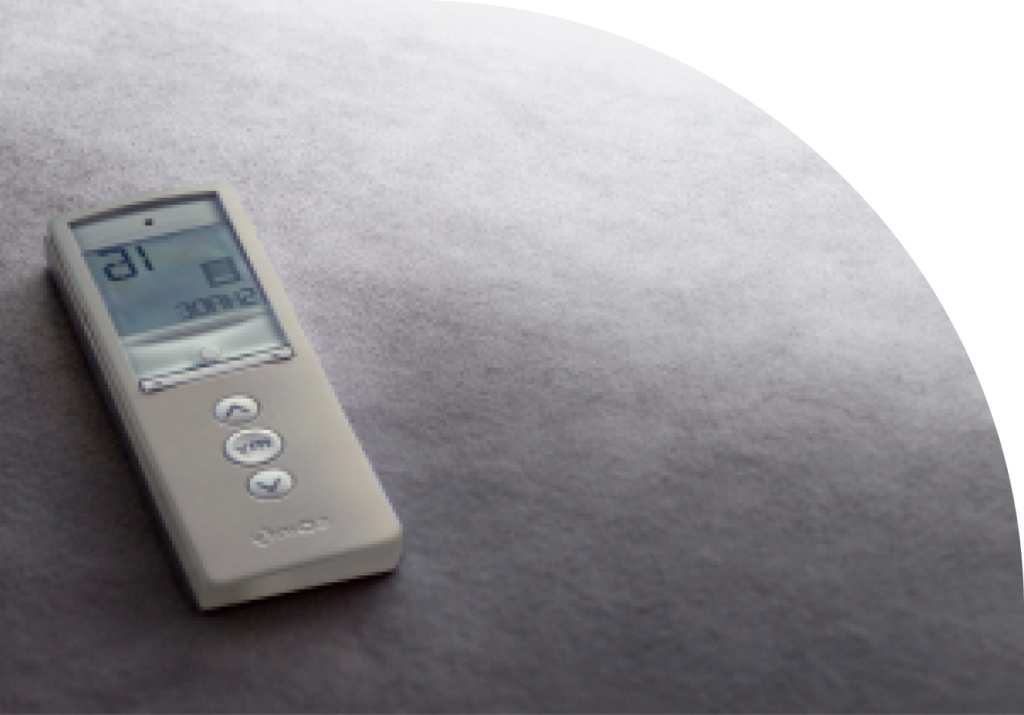 Small, gray shade automation remote laying on a dark gray surface.
